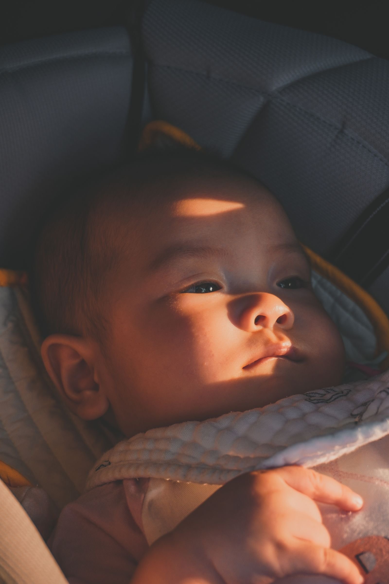 Bebe deitado tranquilamente no bebe conforto, banhado por luz suave