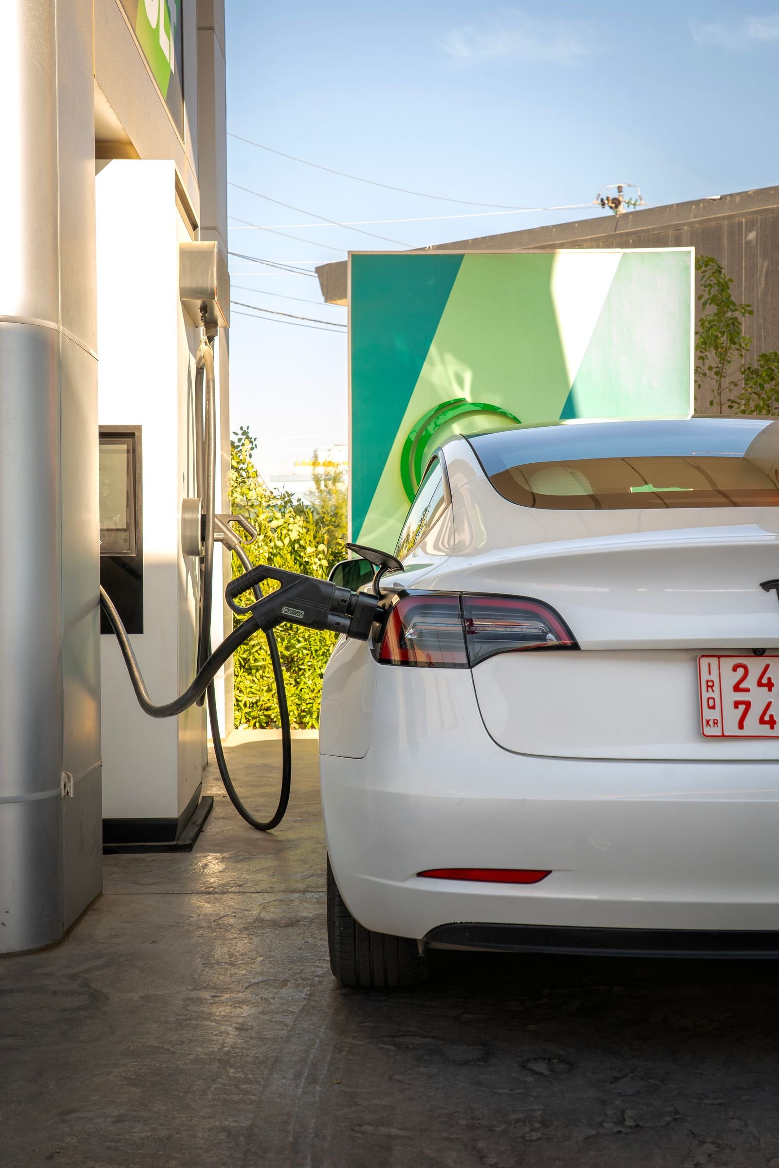 Tesla Model 3 carregando em um posto de recarga ao ar livre durante o dia
