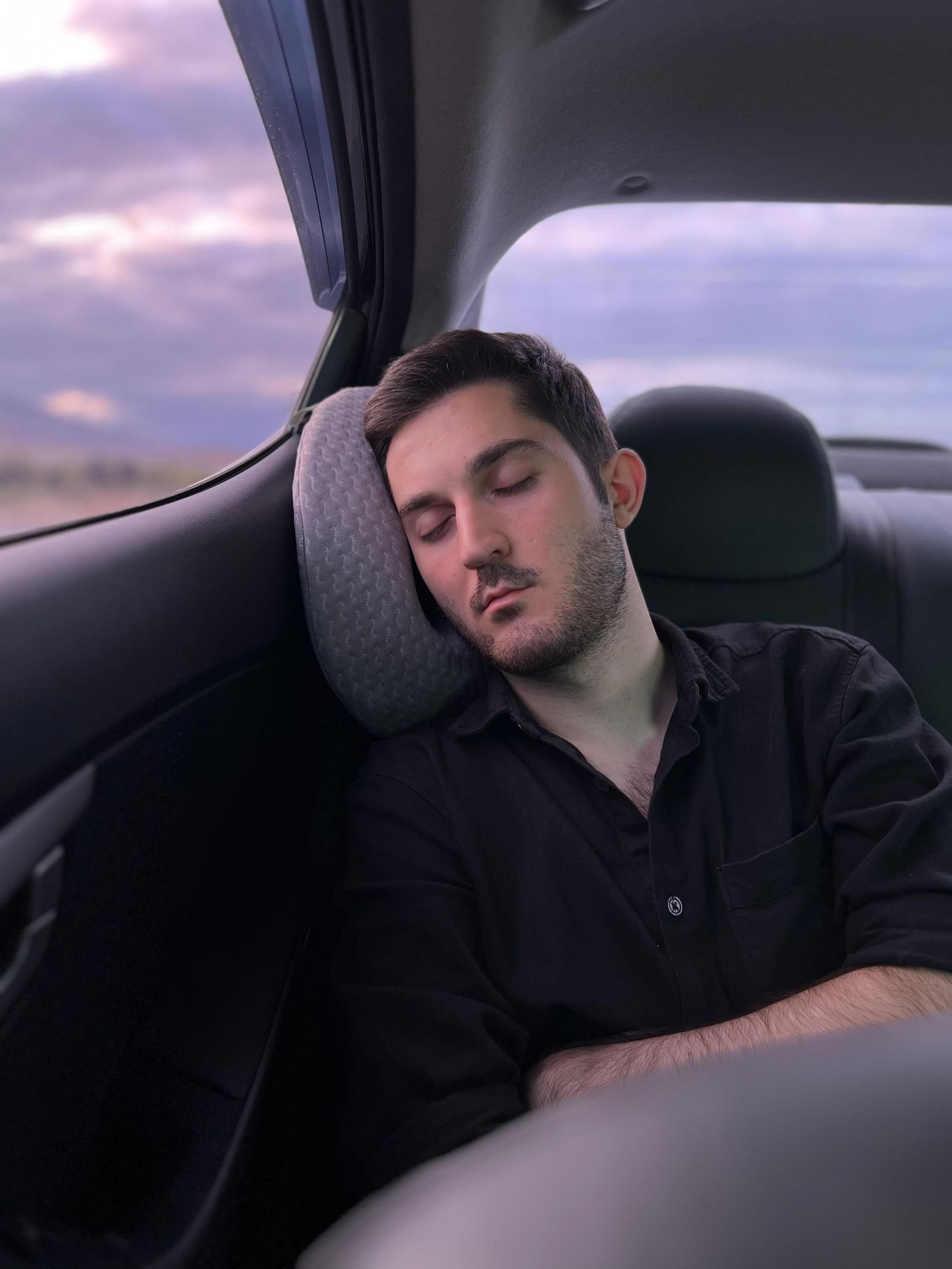 Jovem dormindo confortavelmente no banco de trás do carro durante uma viagem longa