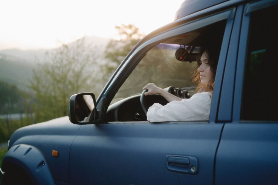 Mulher dirigindo um SUV por uma paisagem cenica ao por do sol, explorando sozinha