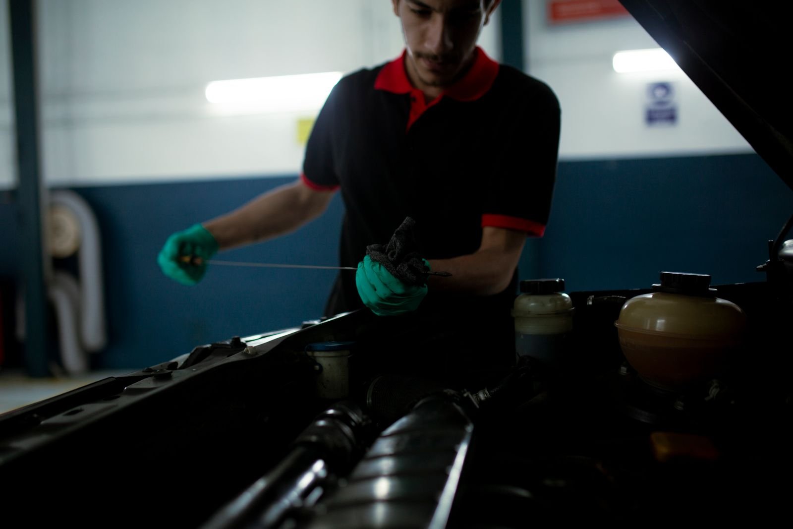 Mecanico examinando o nivel de oleo do motor usando uma vareta medidora em oficina